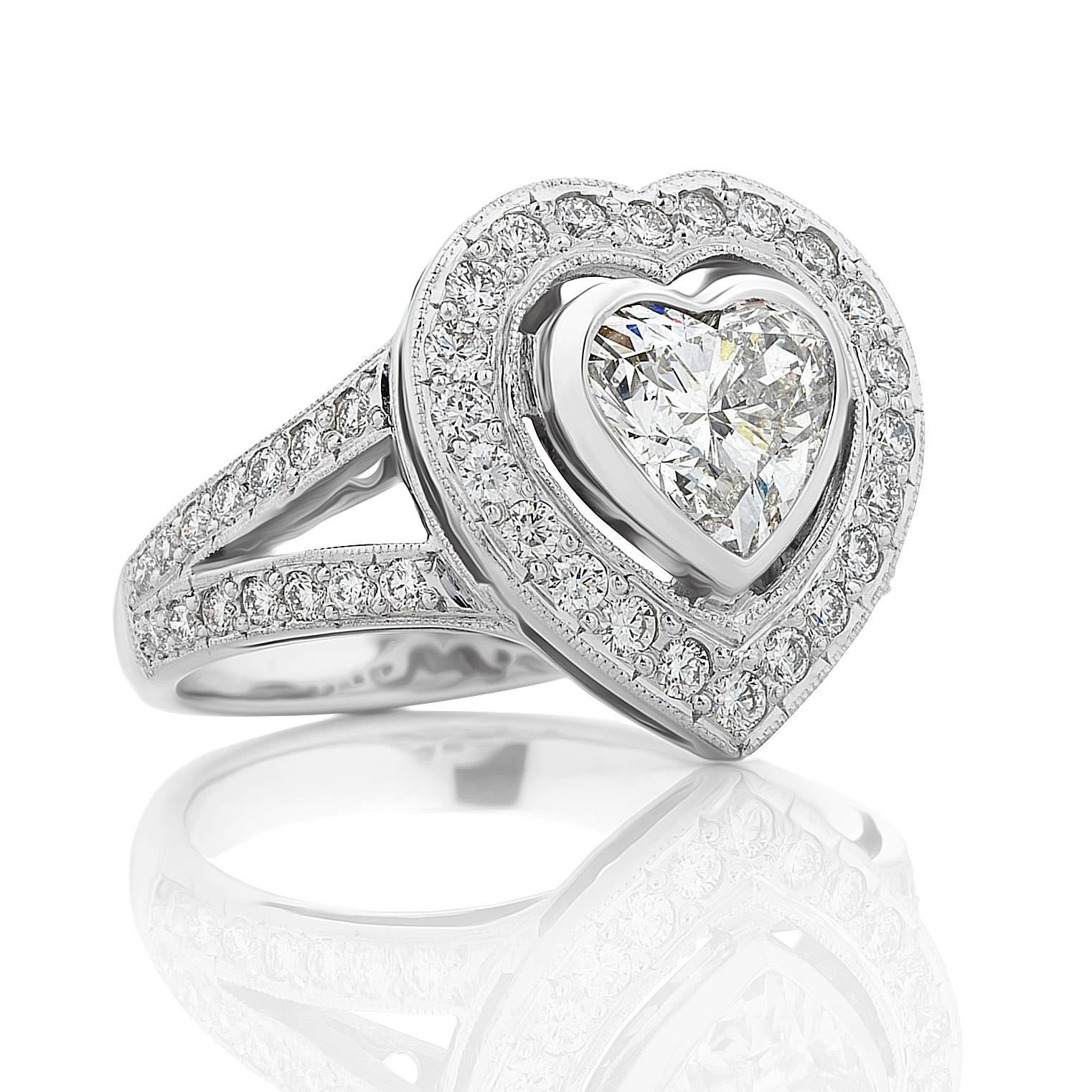 Handmade 18 karat white gold diamond Halo style ring.  Centred with one bezel set 1.14ct heart shaped diamond - GIA report stating G colour Si1 clarity.  Beautifully proportioned. Surrounded with grain set brilliant cut diamond and a V shaped split