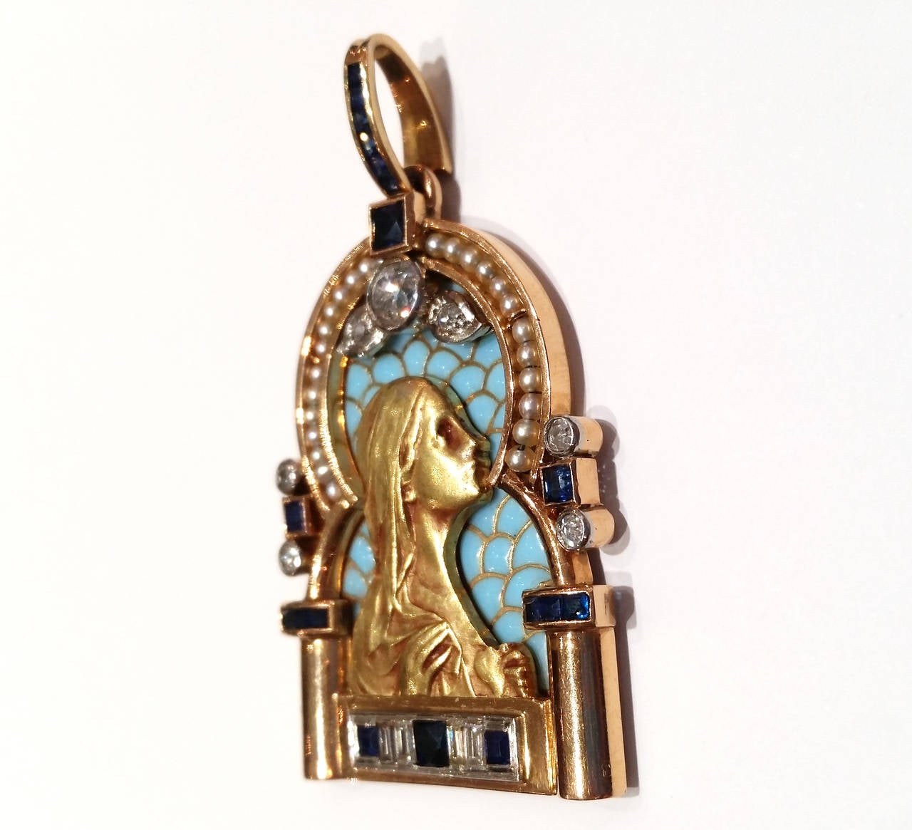 Beautiful pendant depicting Virgin Mary in yellow gold, with blue plique-a-jour enamel, pearls, diamond and sapphires.

Central diamond is an old European cut weighting 0.30ct.