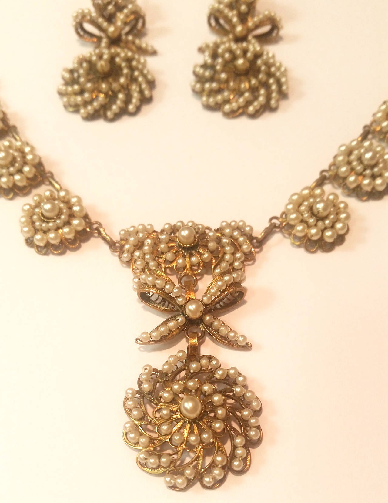 Amazing 19th Century golden filigree suite with rosettes and bows made of little pearls.

Necklace. 30.05 grams. Length 42cm. Height 5cm
Earrings. 9.05 grams. Length 6cm. Width 2 centimeters.