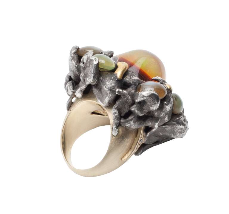 The 'Water Berry' ring is designed by Spanish artist and jeweler, Vicente Gracia. The central cabochon opal is surrounded by seven smaller cabochon cat´s eye chrysoberyl stones. The chrysoberyl stones have an approximate total weight of 13.68ct.