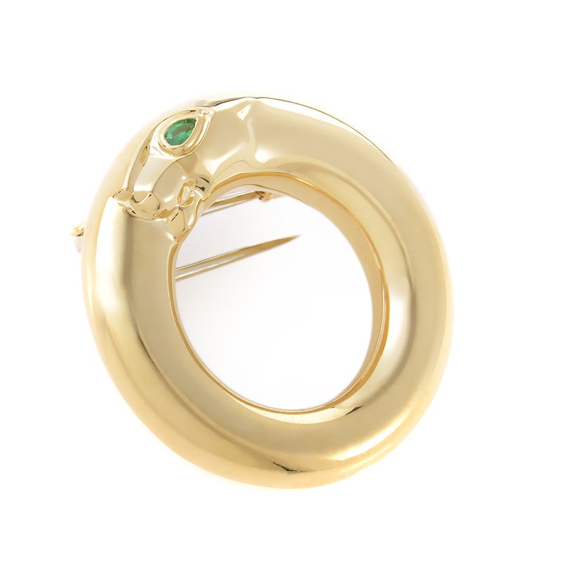 An exceptional piece of jewelry, this is an eye-catching brooch with a glimmering, reflecting surface of alluring smoothness. It's made of 18K yellow gold with a beautiful emerald stone representing the eye of the beast-like decoration on the