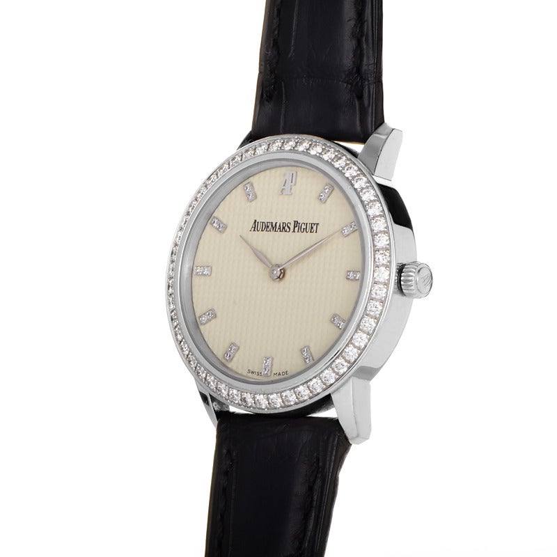 Audemars Piguet lady's 18K white gold manually wound wristwatch with a 48 diamond-set bezel on a black crocodile leather strap. Watch displays indication of the hours and minutes on an ivory dial with diamond index hour markers.

Included Items: