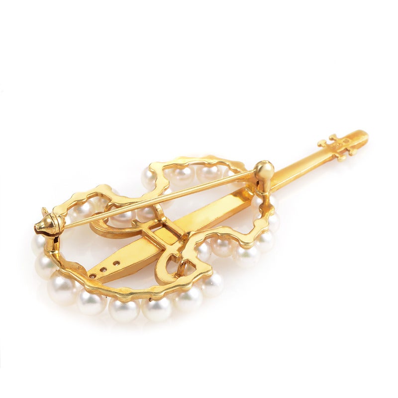 The perfect accessory for a musically inclined lady- the Mikimoto 18K Yellow Gold Diamond & Pearl Cello Brooch. This brooch is made of glimmering 18K yellow gold and features a body set with petite white pearls. Lastly, the bridge is set with