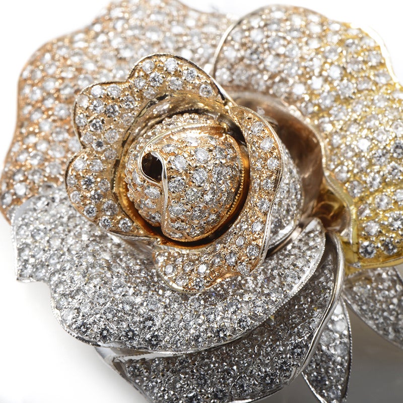 Bold, brilliant, and beautiful are just a few words to describe this incredibly decadent antique brooch. The brooch is shaped like a rose in the height of its bloom and is made of a combination of 18K white, rose, and yellow gold. What makes this