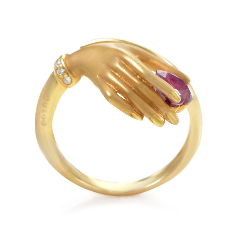 There aren’t many jewelry pieces showing such affection for jewels as this marvelous 18K yellow gold Carrera y Carrera ring depicting a hand gracefully holding an attractive heart-shaped ruby stone. The hand is embellished with several diamond