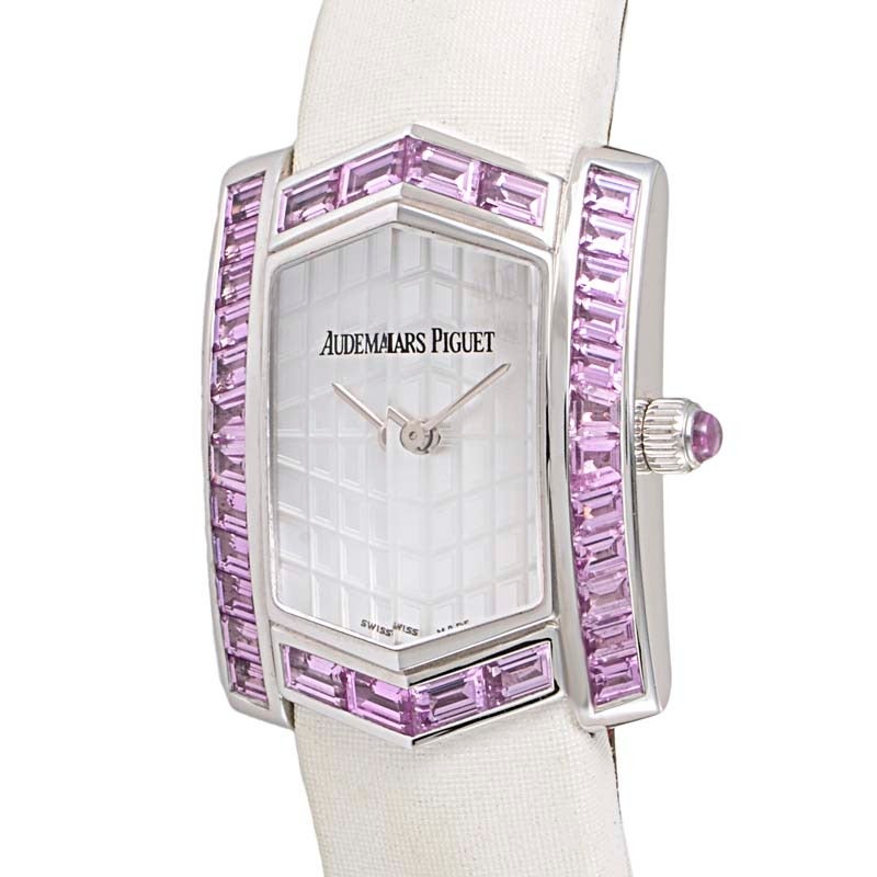 Audemars Piguet lady's 18K white gold quartz wristwatch with pink sapphire baguette-set bezel on a white satin strap. Watch displays indication of hours and minutes on a mother of pearl dial.