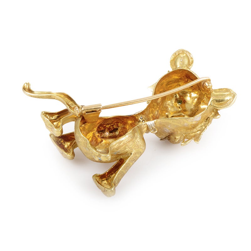 Made of shimmering 18K yellow gold, this attractive brooch in shape of a wild cat also features subtle diamonds on the animal's necklace and emerald stones as its eyes.