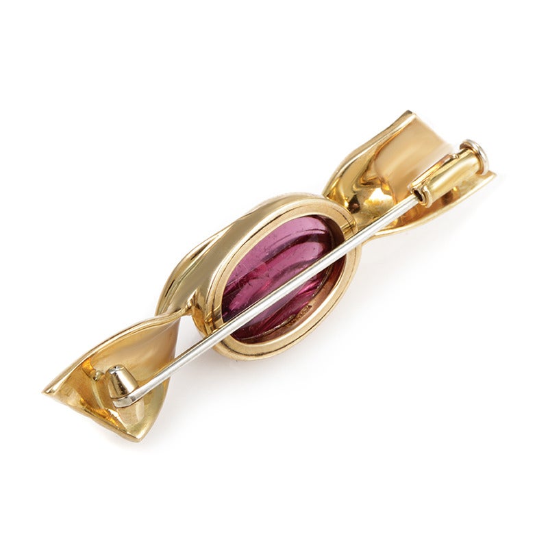 Shaped like a wrapped candy, this enchanting 18K yellow gold brooch is embellished with a delightful tourmaline stone, with its surface harmoniously following the impressive lines of the rest of the piece.