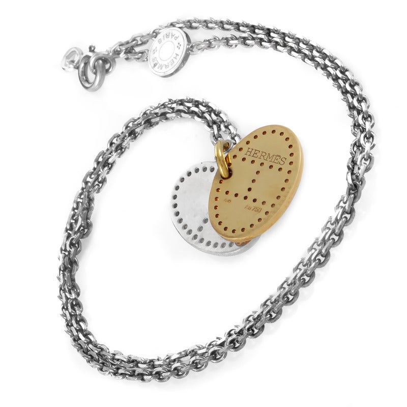 An interesting two-part pendant made of silver and 18K yellow gold and reminiscent of military identification tags hangs from the handsome silver chain of this remarkable necklace from Hermes.

Included Items: Manufacturer's Box

Approximate