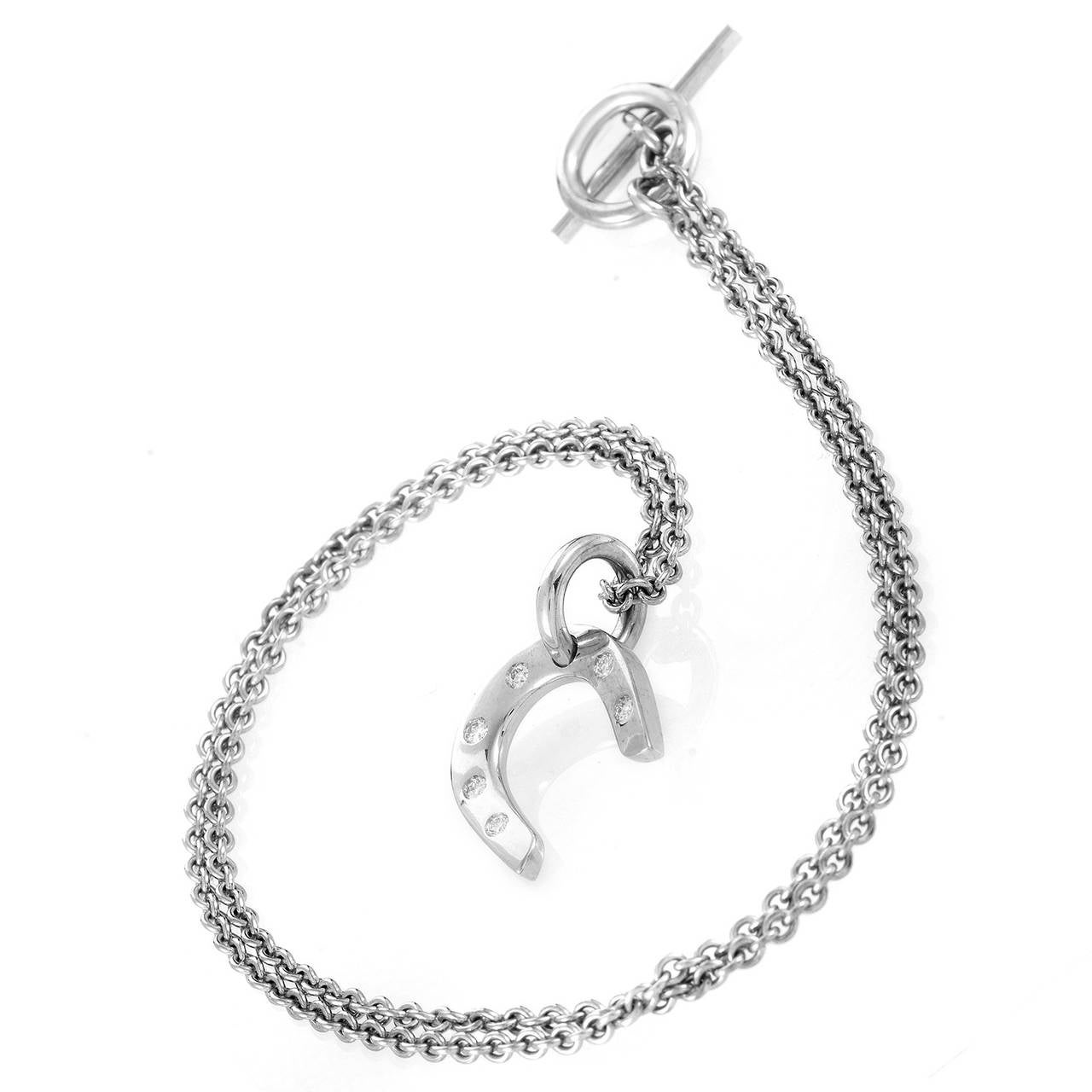 Made of shimmering 18K white gold, this elegant necklace from Hermes is comprised of a classic, subtle chain with a toggle clasp and a symbolic pendant in the form of a horseshoe set with delicate diamonds.