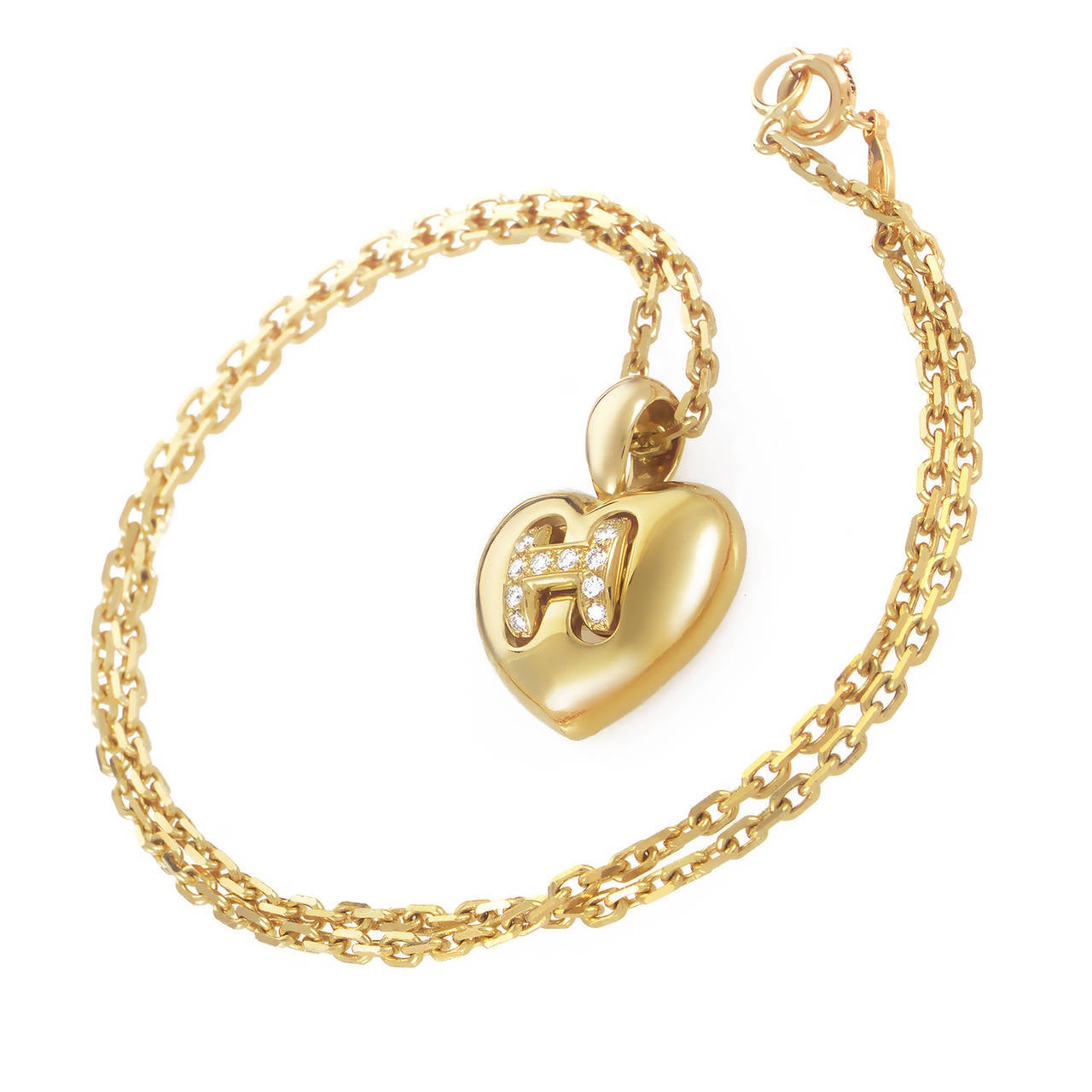 Dangling from a dependable, elegant 18K yellow gold chain with a spring ring, the romantic heart pendant of this feminine necklace from Hermes incorporates the characteristic H-shaped element set with diamonds for an extra touch of