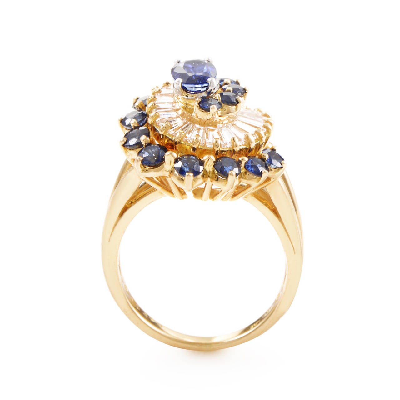 This uniquely designed Oscar Heyman ring is an absolute delight to wear as well as to behold. The ring is made from 18K yellow gold with platinum prongs that hold the blue sapphire main stone in place. 1.20 carats of sapphires combined with 2.50