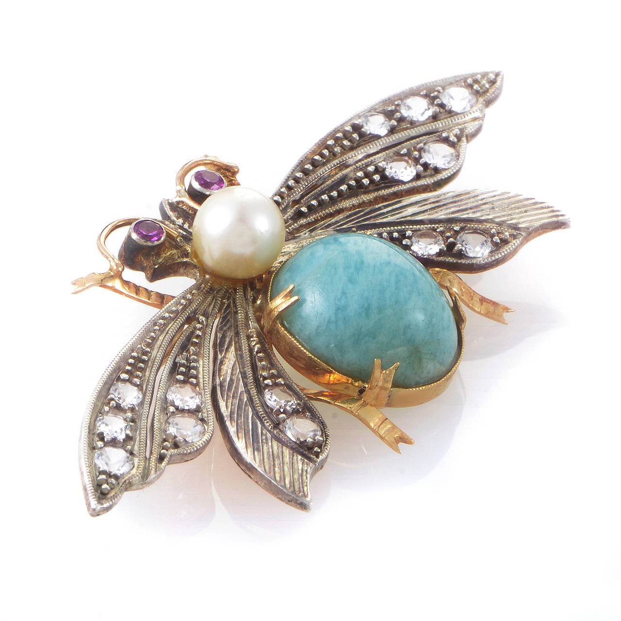 Beautifully designed and bold as can be, this brooch is the perfect collector's item. The brooch is shaped like a moth and is made of a combination of 18K yellow gold and silver. Boasting white sapphires, rubies, jasper, and pearls, this brooch is a