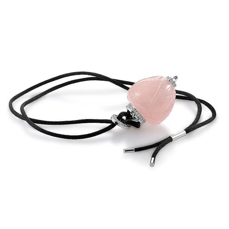 This exotic pendant necklace from Cartier is extremely rare, and is the perfect collector's item for a true jewelry lover. The necklace is a black satin cord from which hangs a luxurious perfume bottle-shaped pendant. The rose quartz bottle is