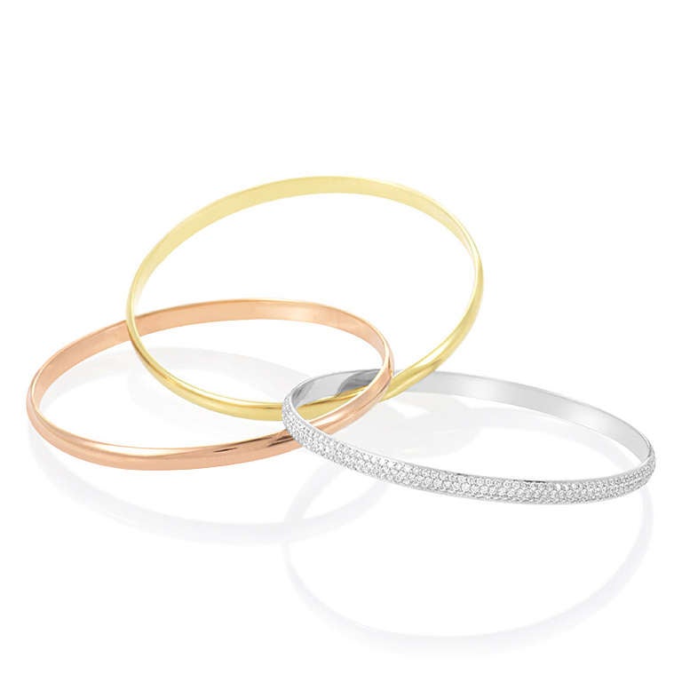 A gorgeous combination of gold and diamonds makes this bangle bracelet from Cartier's Trinity collection in a class by itself. The bracelet is comprised of three 18K gold bands; one rose, one yellow, and one white. Lastly, the white band is set with