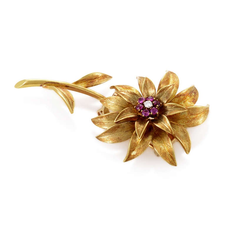 The festive and feminine design of this classic brooch from Tiffany & Co. exudes a timeless elegance. The brooch is made of 18K yellow gold and is shaped like a gorgeous flower. Lastly, the center of the flower is set with ~.40ct of rubies and