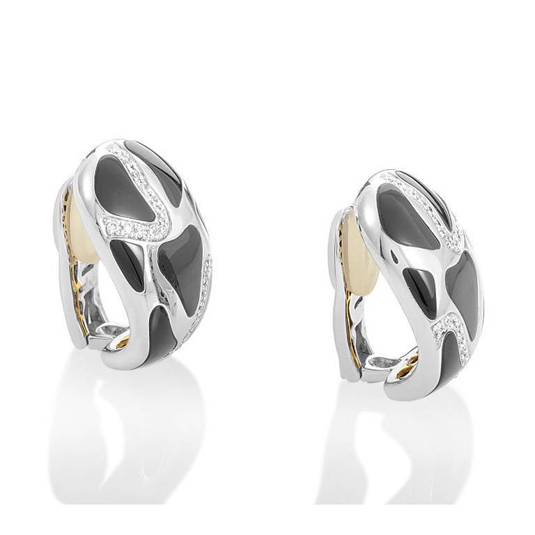 Highly unique and expertly crafted, this pair of huggie earrings from Roberto Coin are in a class by themselves! The earrings are made of 18K white gold with a yellow gold interior accented with a single ruby. Lastly, the ring's exterior is tiled