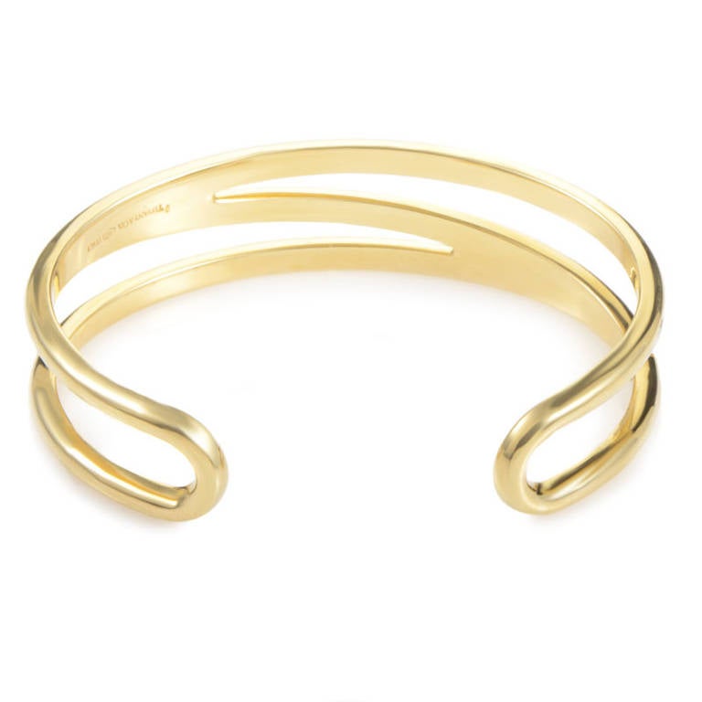 Golden and glorious, this cuff bracelet from Tiffany & Co. has an intricate design that is unlike any other. The bracelet is made of 18K yellow gold and features an openwork design with a zigzag pattern.