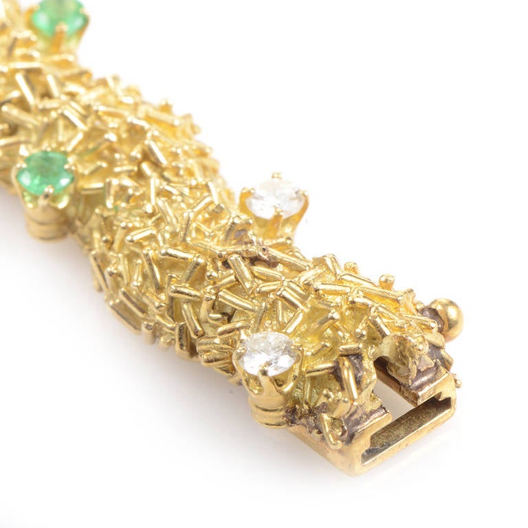 This finely crafted bracelet has a distinct design that is textured and tantalizing. The bracelet is made of 18K yellow gold and is studded with ~.50ct of diamonds and ~.75ct of emeralds.