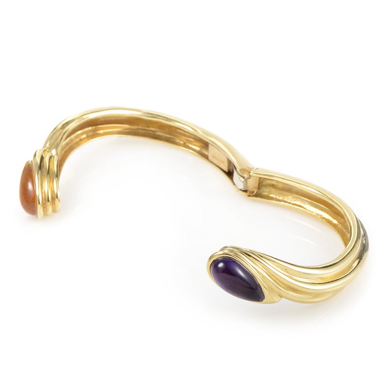 Gucci created perfection when they made this incredibly elegant bangle bracelet. The bracelet is made of 18K yellow gold and is set with two teardrop-shaped cabochons; one citrine and the other amethyst.