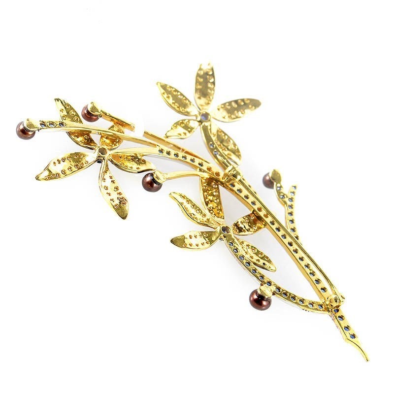 This brooch is colorful and lovely. It is made of 18K yellow gold and is shaped like a flowering branch. The branch boasts a fabulous design of ~.75ct of yellow diamonds, ~1.20ct of blue sapphires and brown pearls.
Retail Price: $3,880.00 (Plus Tax)