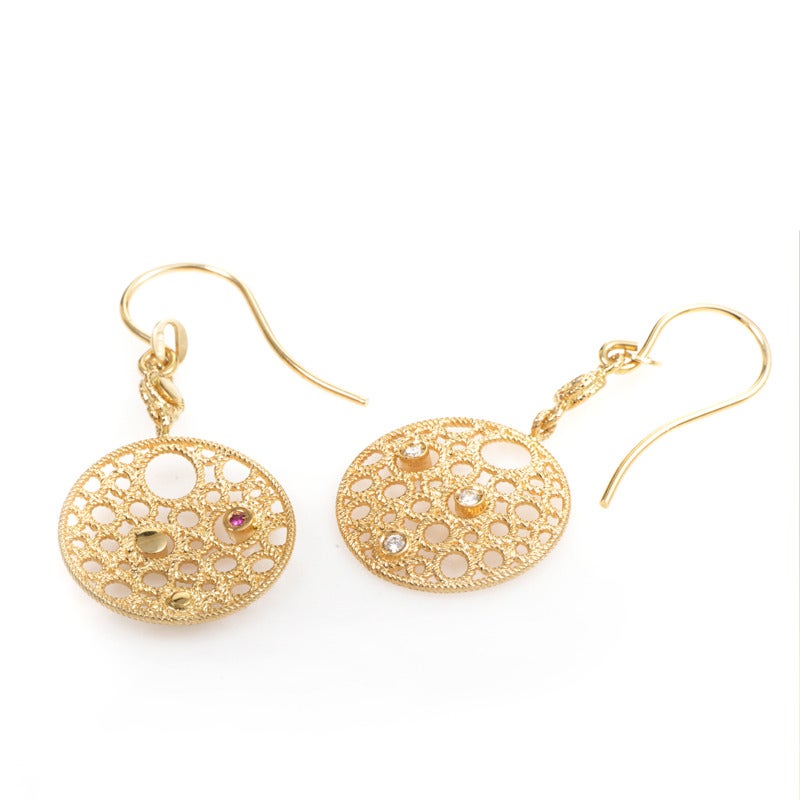 18K yellow gold is spun into perfect hollows to float precious stones in these majestic earrings. The gold is complemented by choice placements of 0.25ct diamonds, plus a shy ruby nestled on the back to signify the earring's authenticity as a