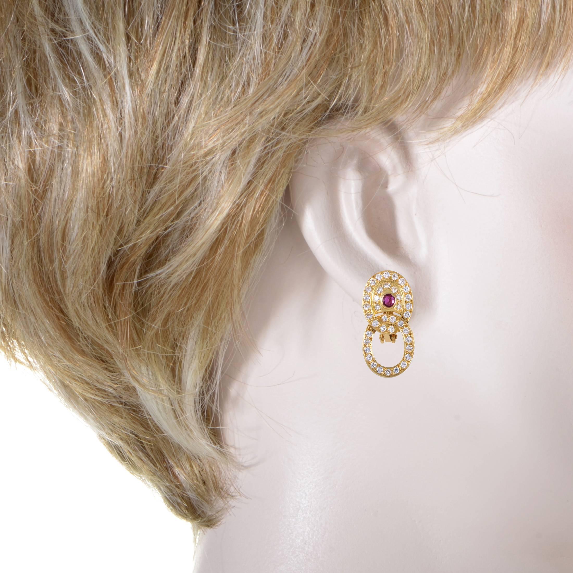 These earrings by Garrard present an eye-catching display. The design unites two 18K yellow gold hoops that are set with 1.25ct of pave diamonds through the contours. The top half of this dazzling performance is centered by a 0.15ct Ruby. These