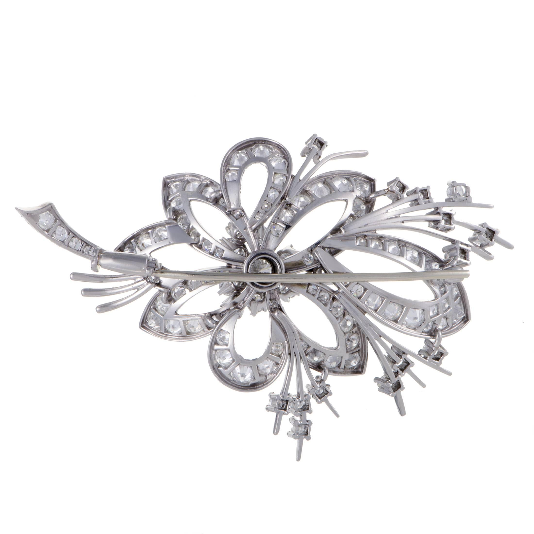 The delightful motif of a flower is presented in majestic fashion in this astonishing brooch made of gleaming platinum and embellished with scintillating side diamonds amounting to 6.80 carats as well as a stunning central stone weighing 0.70ct.
