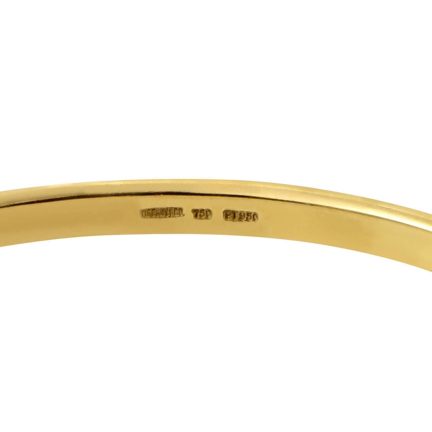 Broken only by the sparkling glare of luminous diamonds set in platinum scattered along in seemingly chaotic fashion, the gleaming, radiant surface of 18K yellow gold in this charming bangle brings a strong sense of understated elegance to this