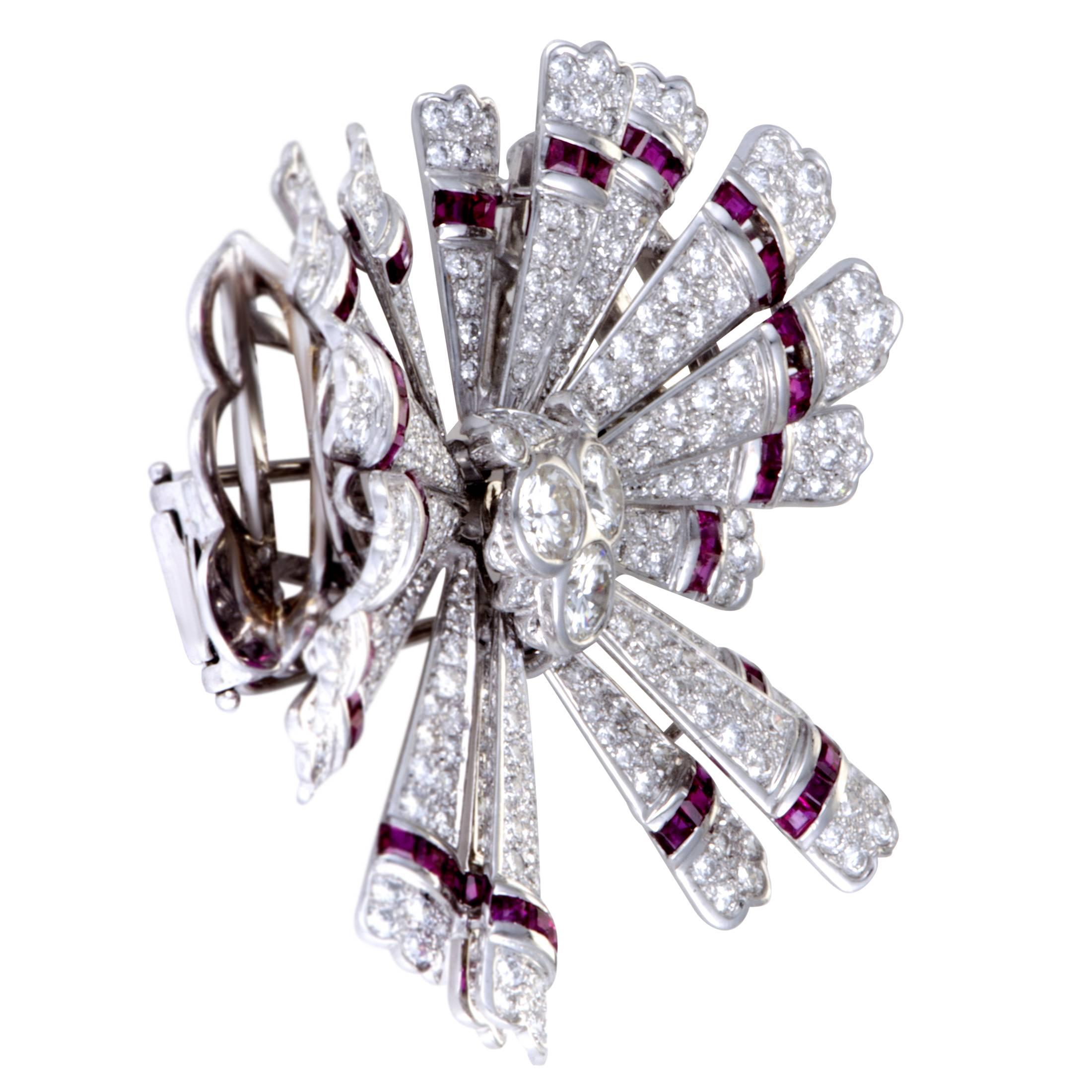 Beautifully crafted in shimmering 18K white gold, this gorgeous brooches by Teone is absolutely exemplary in design and style. The stunning broche is completely embellished in 5.65ct of sparkling diamonds and 2.82ct of exquisite rubies that