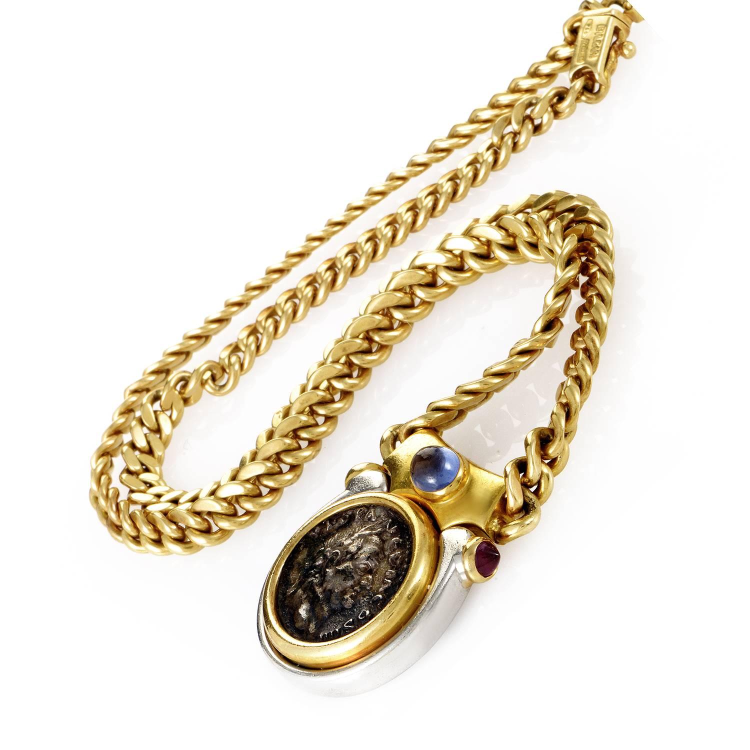 An ancient profile takes center stage in this magnificent production from Bulgari. At the wings of this pendant are two peaking rubies. At center is an engraved portrait on a coin, its features complimented by the sapphire floating overhead. The