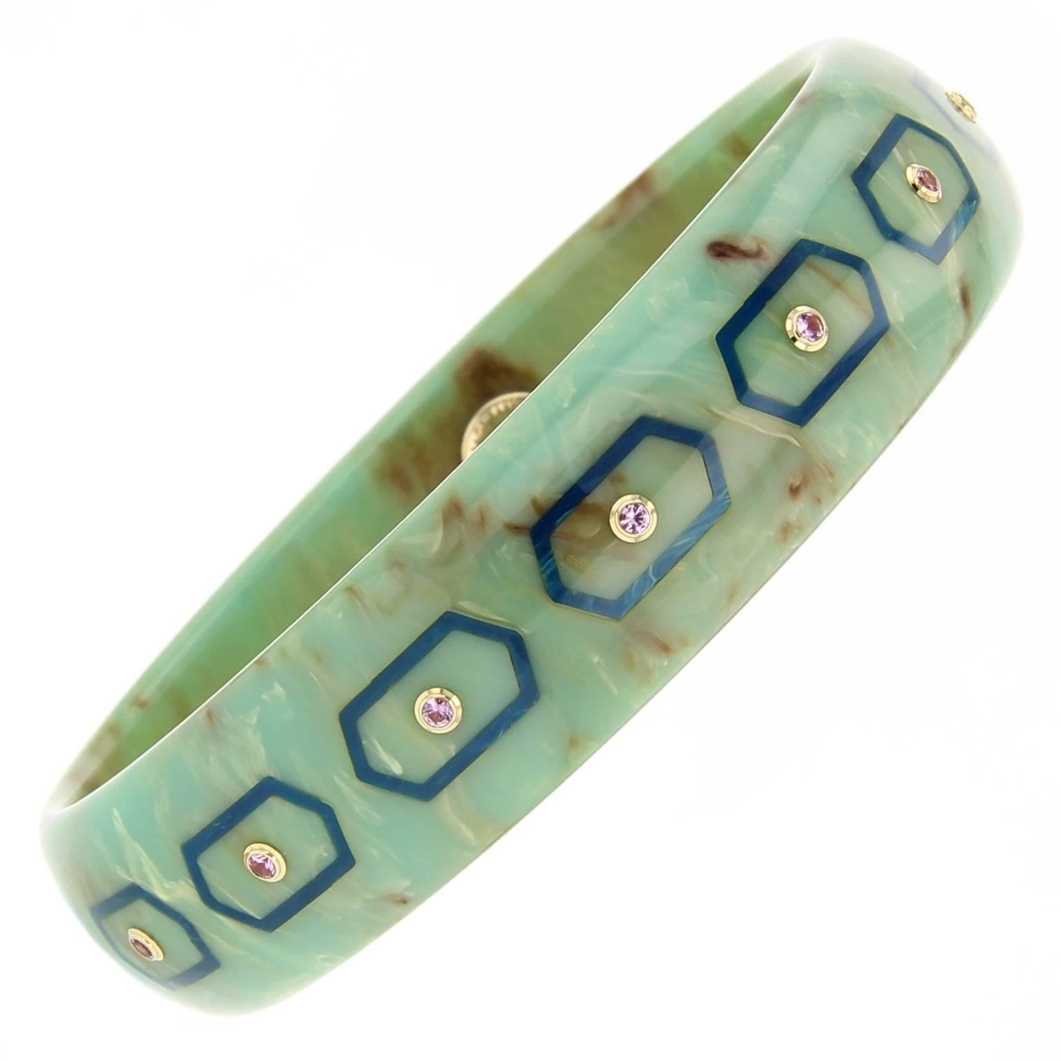 This Mark Davis bangle was handcrafted using marbled turquoise and blue  bakelite.  The bangle is elegantly detailed with elongated hexagonal inlay accented with pink sapphires set in 18k yellow gold bezels. 

Full details below:
• From the Mark