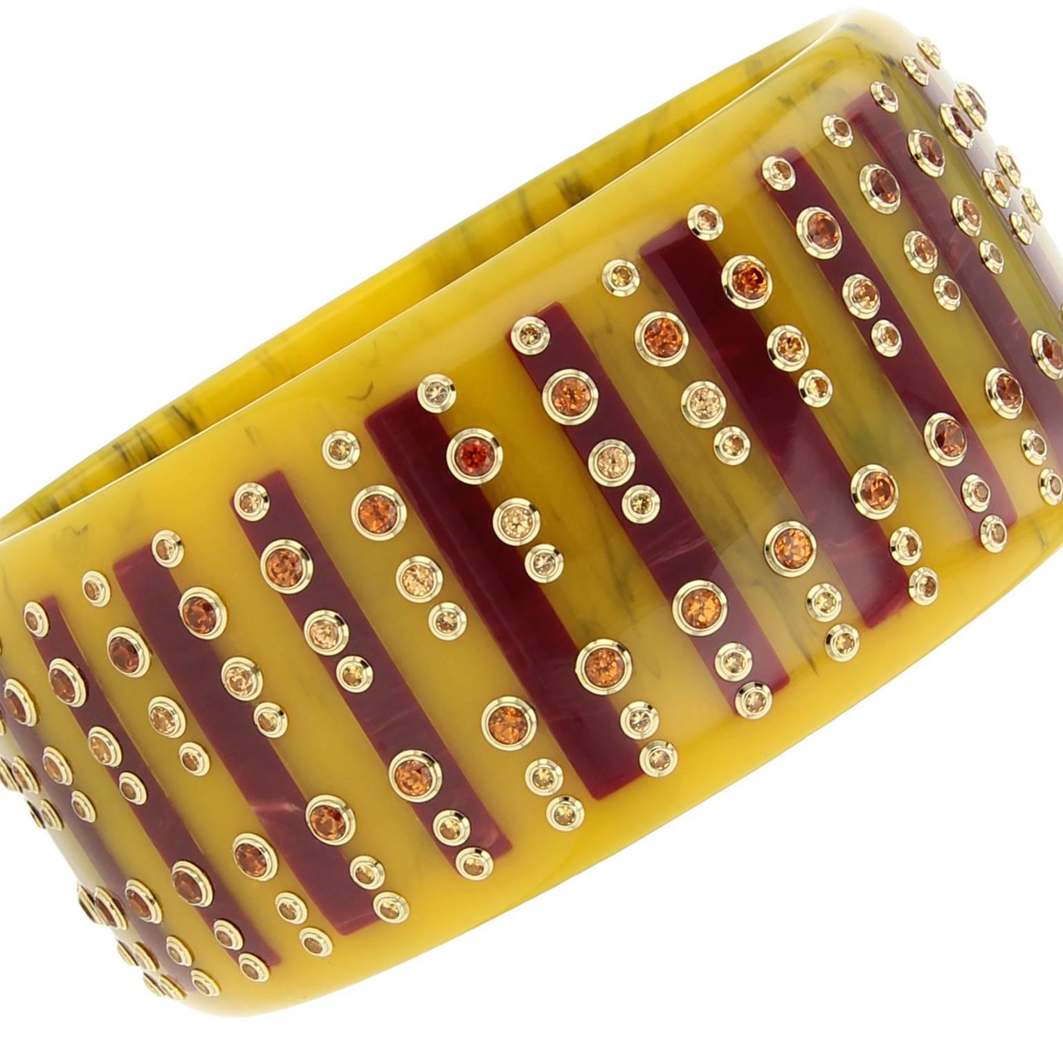 This Mark Davis bangle was handcrafted using mustard yellow and burgundy vintage bakelite. The inlaid elongated rectangles are studded with garnet and yellow sapphire set in 18k yellow gold bezels.

Full details below: 
• From the Mark Davis
