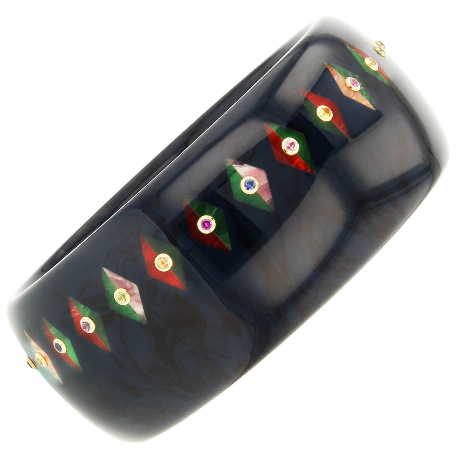This substantial Mark Davis bangle was handcrafted using deep marbled blue and black vintage bakelite.  Inlaid with bicolored lozenges and studded with amethyst, citrine, garnet, peridot, blue sapphire, pink sapphire, and yellow sapphire set in 18k