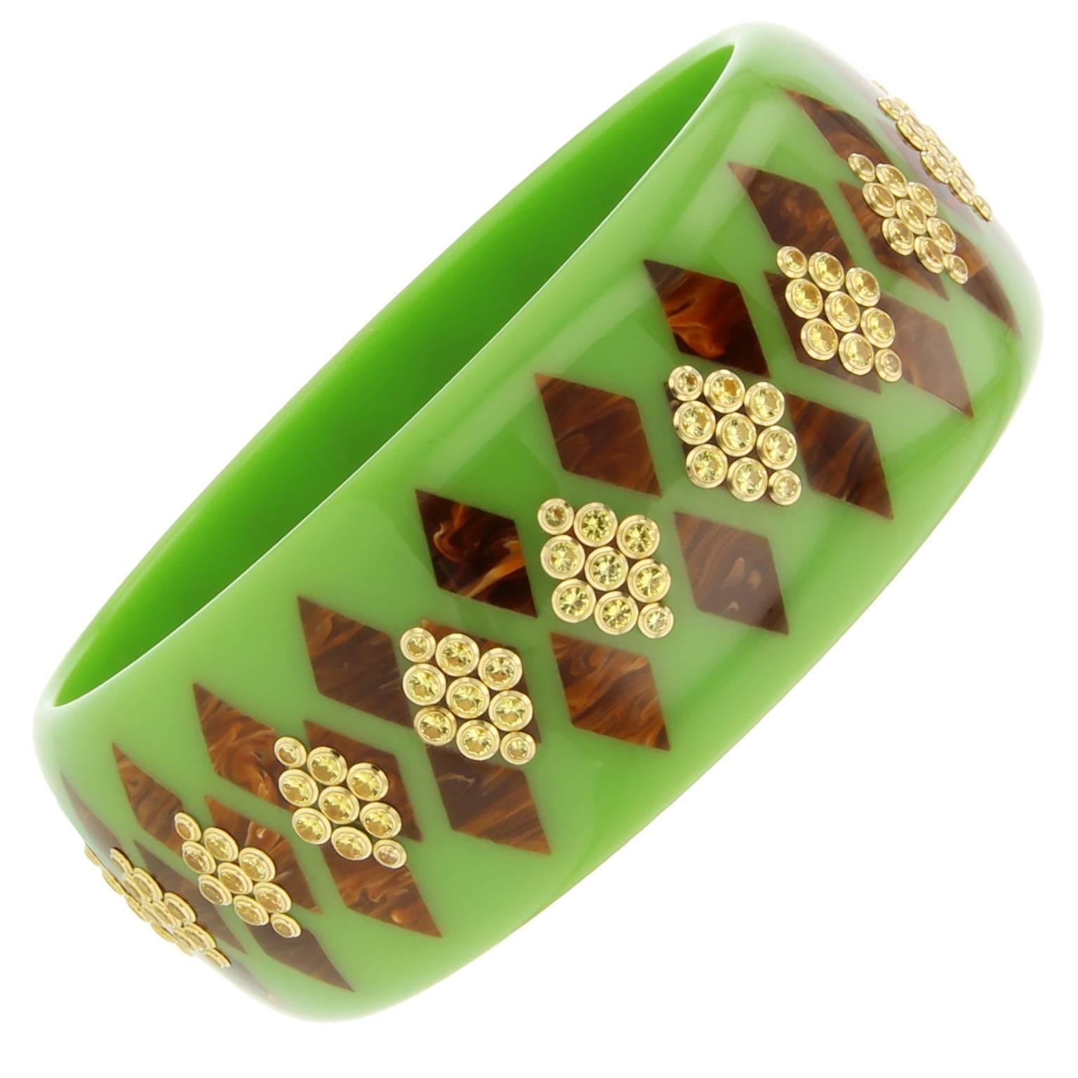 This solid green and marbled brown vintage bakelite bangle is decorated with diamond-shaped inlay work.  Clusters of yellow sapphire bezel-set in 18k yellow gold echo the diamond shape pattern. 

Full details below:
• From the Mark Davis Collector