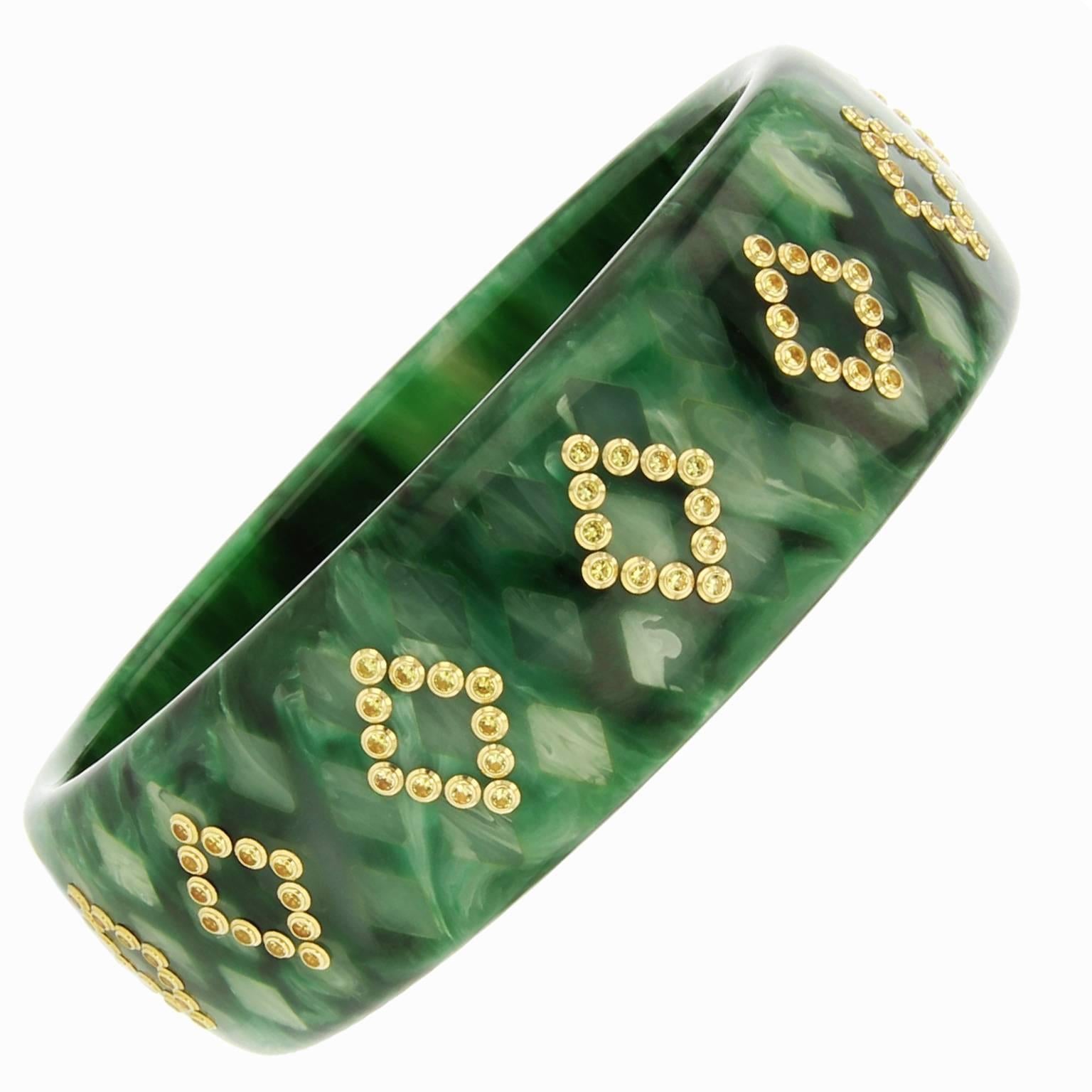 This Mark Davis marbled green vintage bakelite bangle is finely inlaid with lighter green bakelite creating a subtle diamond pattern. Yellow sapphires, bezel-set in 18k yellow gold create a diamond-shaped pattern overlaid around the bangle.  

Full
