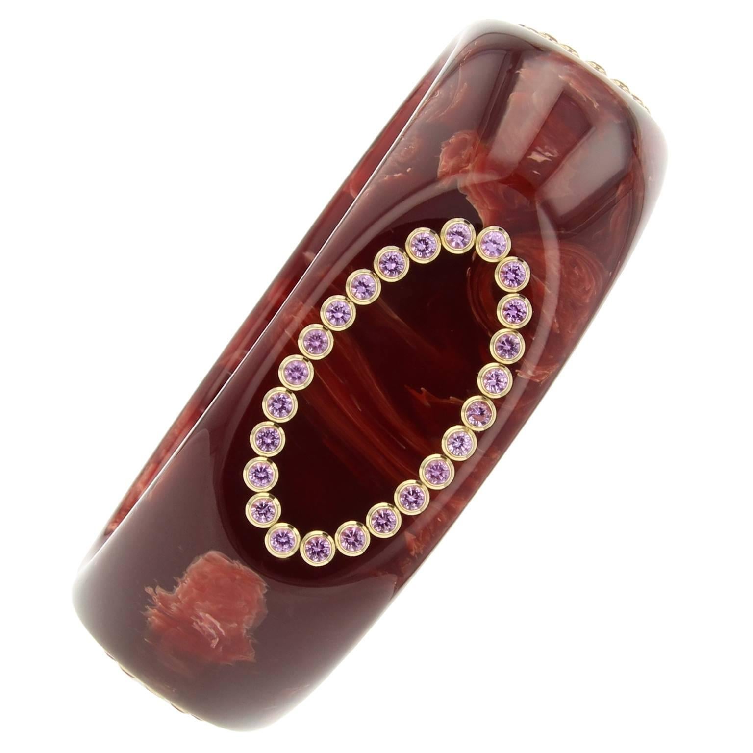 This rounded, square-shaped Mark Davis Bangle was handcrafted using marbled burgundy vintage bakelite.  The applied oval motifs are created using very fine pink sapphires set in 18k yellow gold bezels.  

Full details below: 
• From the Mark Davis