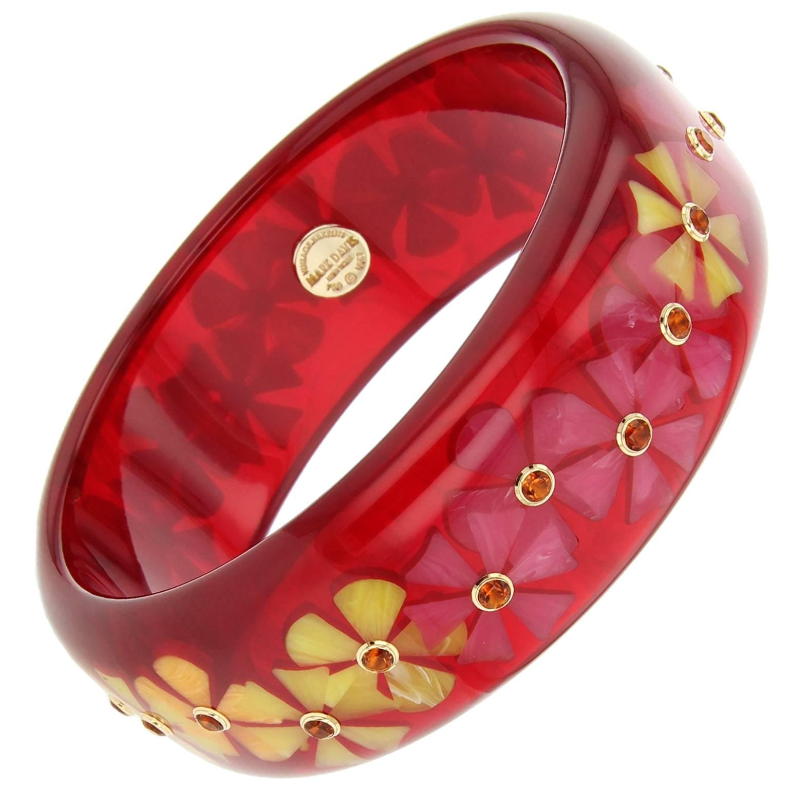 This unique and charming Mark Davis bangle was handcrafted of vintage prystal burgundy bakelite.  The two distinct flower motifs were intricately inlaid with pieces of orange, yellow and pink bakelite.  Each flower is centered with a citrine