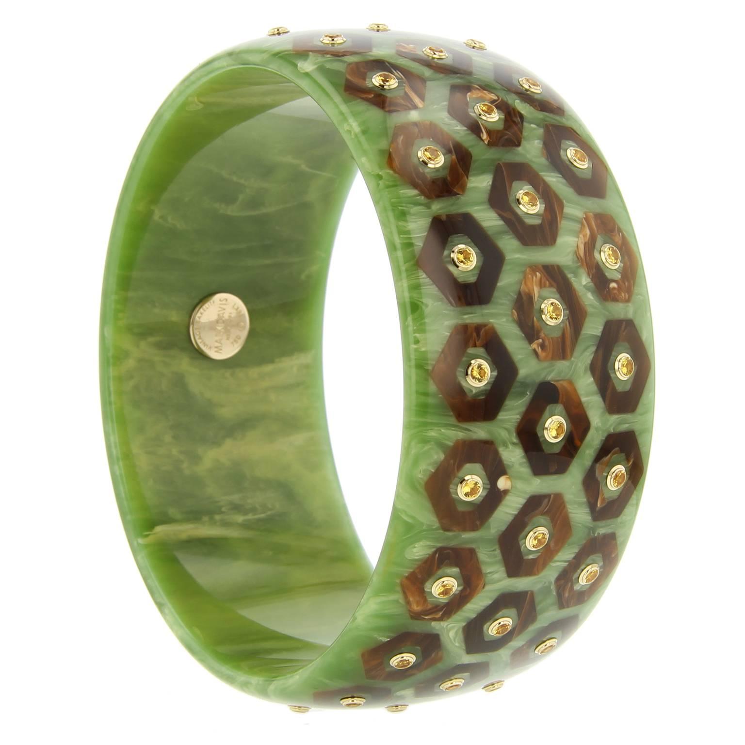 This Mark Davis bangle was handcrafted of marbled green vintage bakelite and meticulously inlayed with hexagonal shaped pieces of brown bakelite. Each hexagon is centered with a fine yellow sapphire, bezel-set in 18k yellow gold. 

Full details