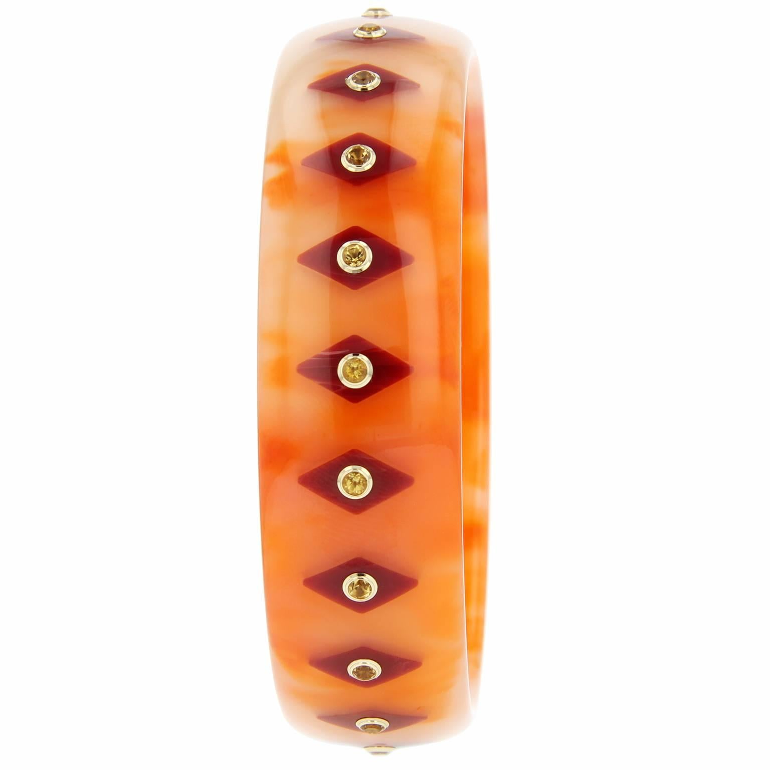 This uniquely colored Mark Davis bangle was handcrafted of marbled orange and pink vintage bakelite and inlayed with diamond-shaped pieces of burgundy bakelite. Each station is centered with a citrine bezel-set in 18k yellow gold. 

Full details