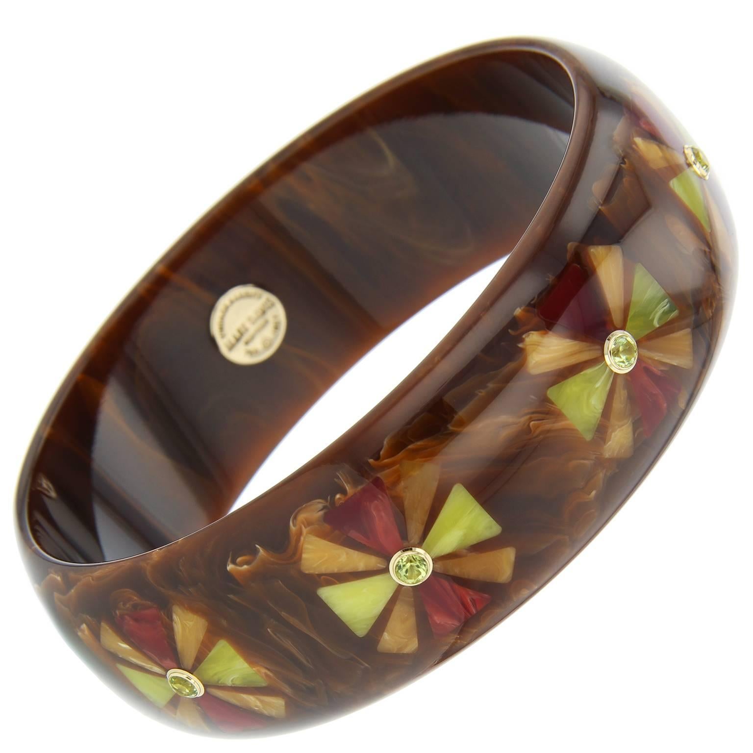 This incredible Mark Davis bangle was handcrafted using marbled brown vintage bakelite.  A Maltese cross motif is formed by the precise inlay of yellow, orange and burgundy vintage bakelite pieces. Centering each motif is a peridot, bezel-set in 18k