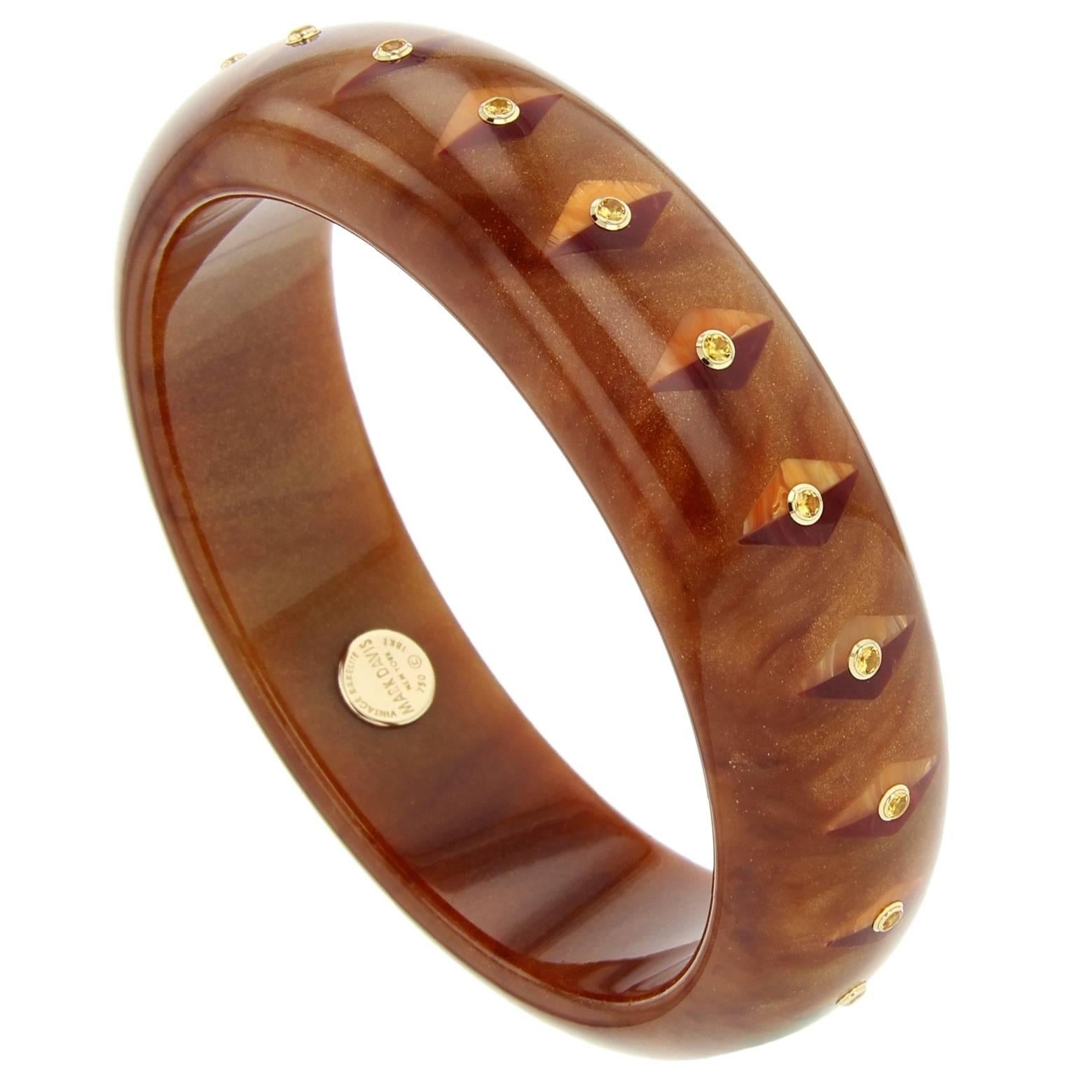 This elegant Mark Davis bangle is made of marbled brown and gold vintage bakelite. Precisely inlaid with a lozenge-shaped motif composed of half orange and half burgundy vintage bakelite pieces. Finished with lively yellow sapphires bezel-set in 18k