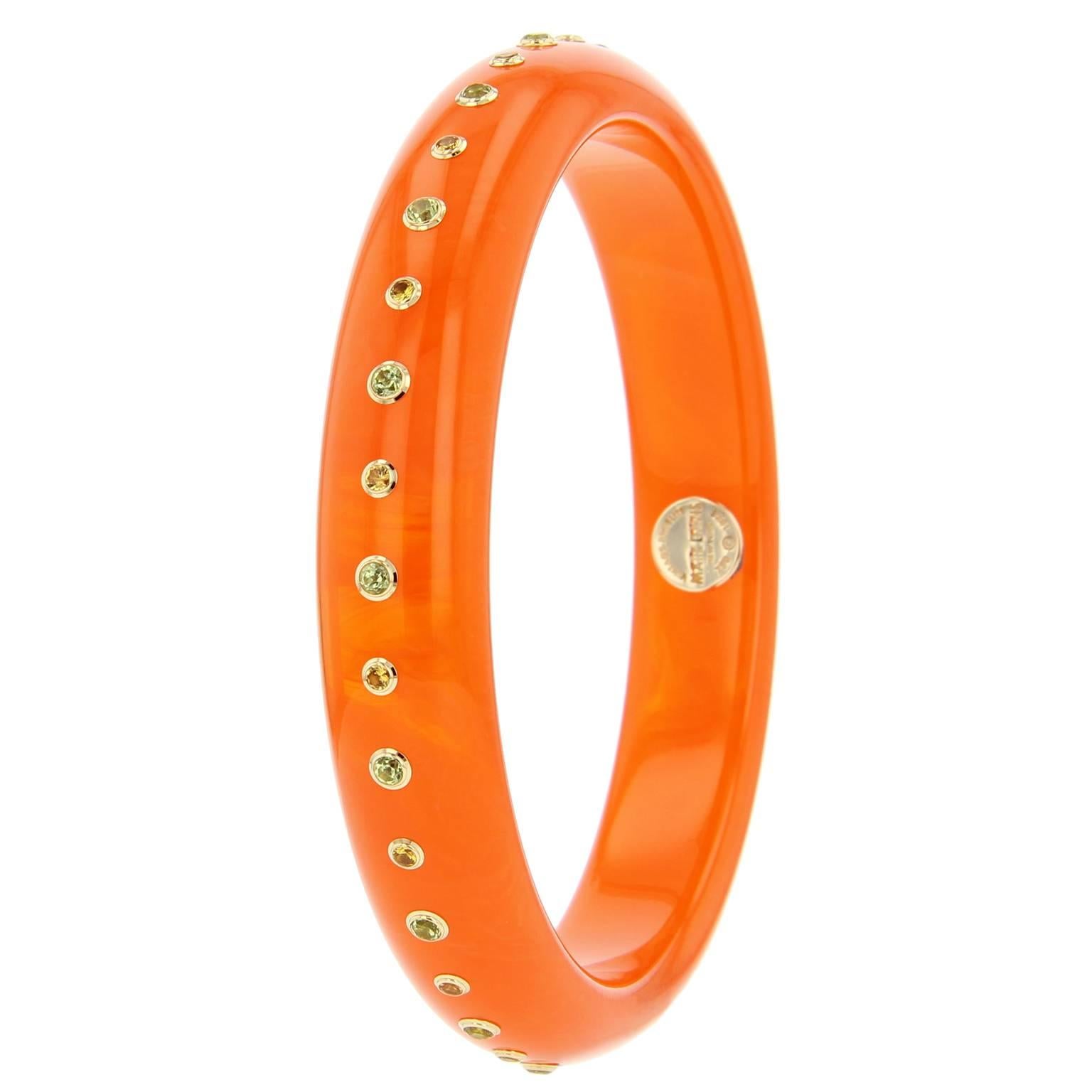 This fiery bangle is part of the Mark Davis Bakelite Collection. It was handcrafted using translucent orange vintage bakelite and studded with peridot and fine yellow sapphire, bezel-set in 18k yellow gold.    

Full details below: 
• From the Mark