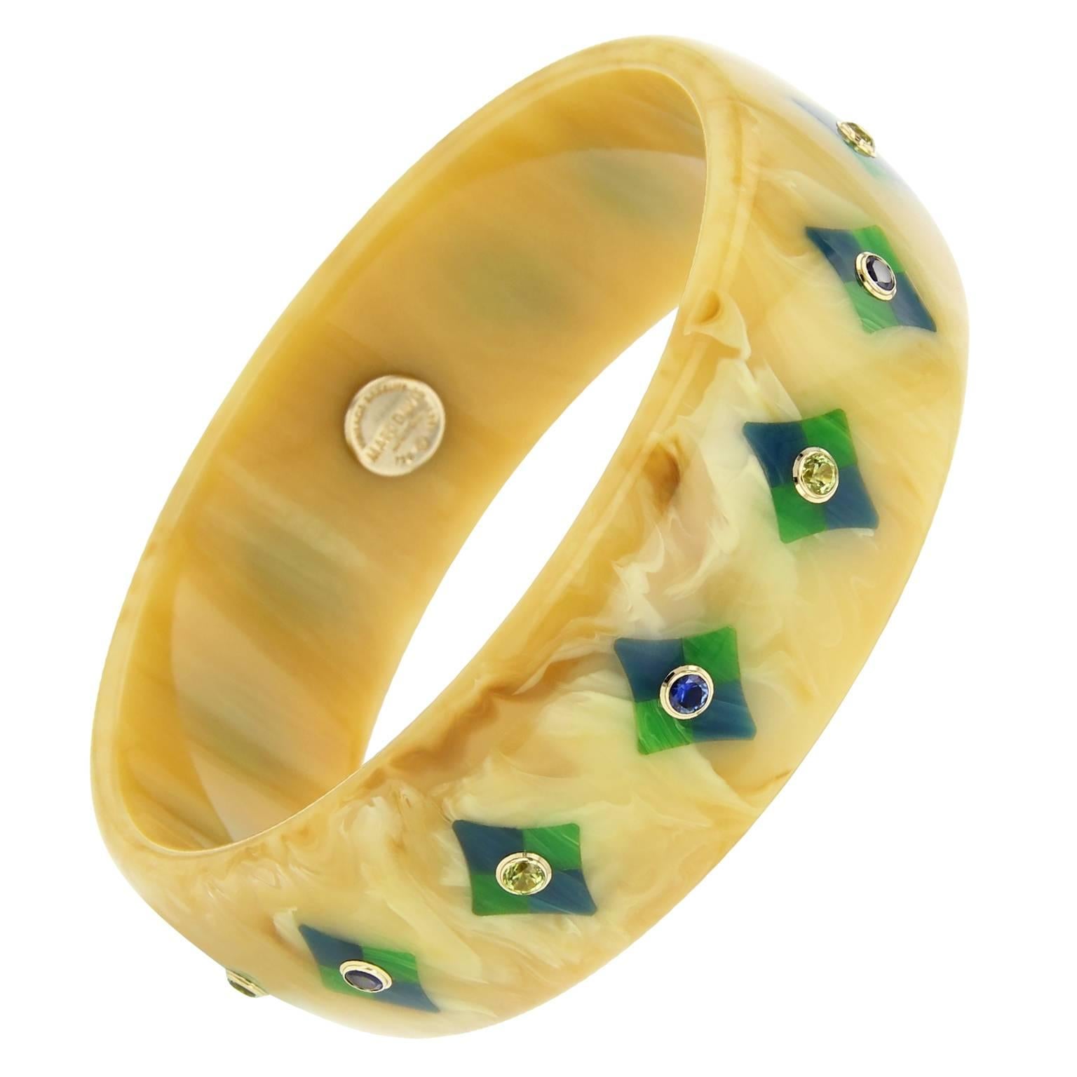 This warm beige and brown Mark Davis bangle was handcrafted using vintage marbled bakelite. The diamond-shaped mosaic pattern was precisely inlaid with pieces of blue and green bakelite.  Each diamond shape is centered with a peridot or fine blue
