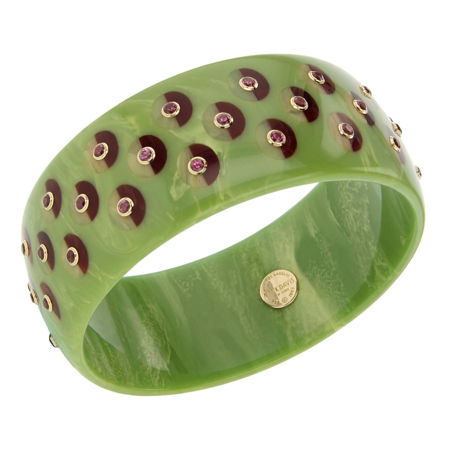This Mark Davis bangle was handcrafted using marbled green vintage bakelite.  Precisely inlaid with a circular motif of half burgundy and beige bakelite pieces. Studded with rhodolite garnet bezel-set in 18k yellow gold.

Full details below: 
• From