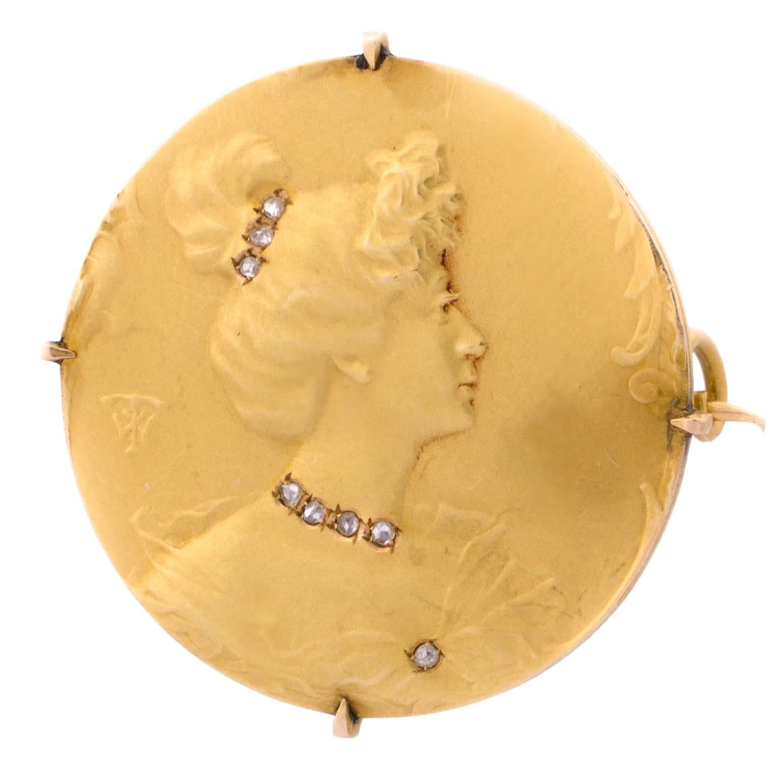 Late 19th century Art Nouveau brooch in matte gold with a female bust relief decorated with 8 rose cut diamonds, signed with unidentified mark.