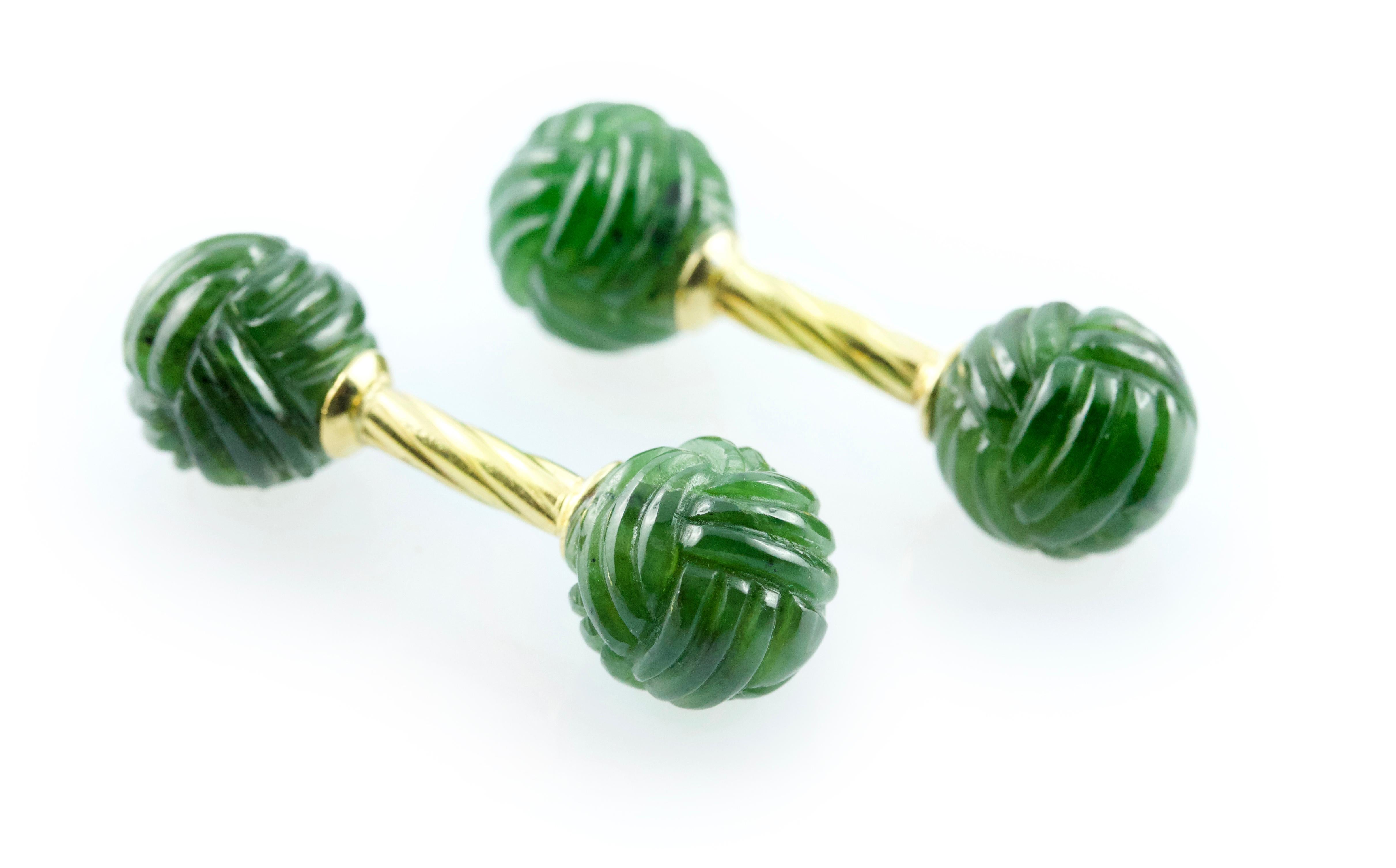 This exquisite pair of cufflinks is made in jade and its front face and toggle are both shaped as spheres whose texture is carved to give the appearance of a ball of yarn. The vivid color of these elements is beautifully complemented by the warm