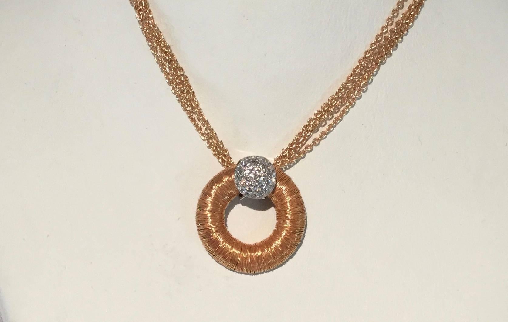 18K rose gold wire wrap circle with white gold diamond pave set accent on a 4 strand 18K rose gold chain. The pendant contains 0.15 carat of diamonds and the necklace weighs 11.5 grams.