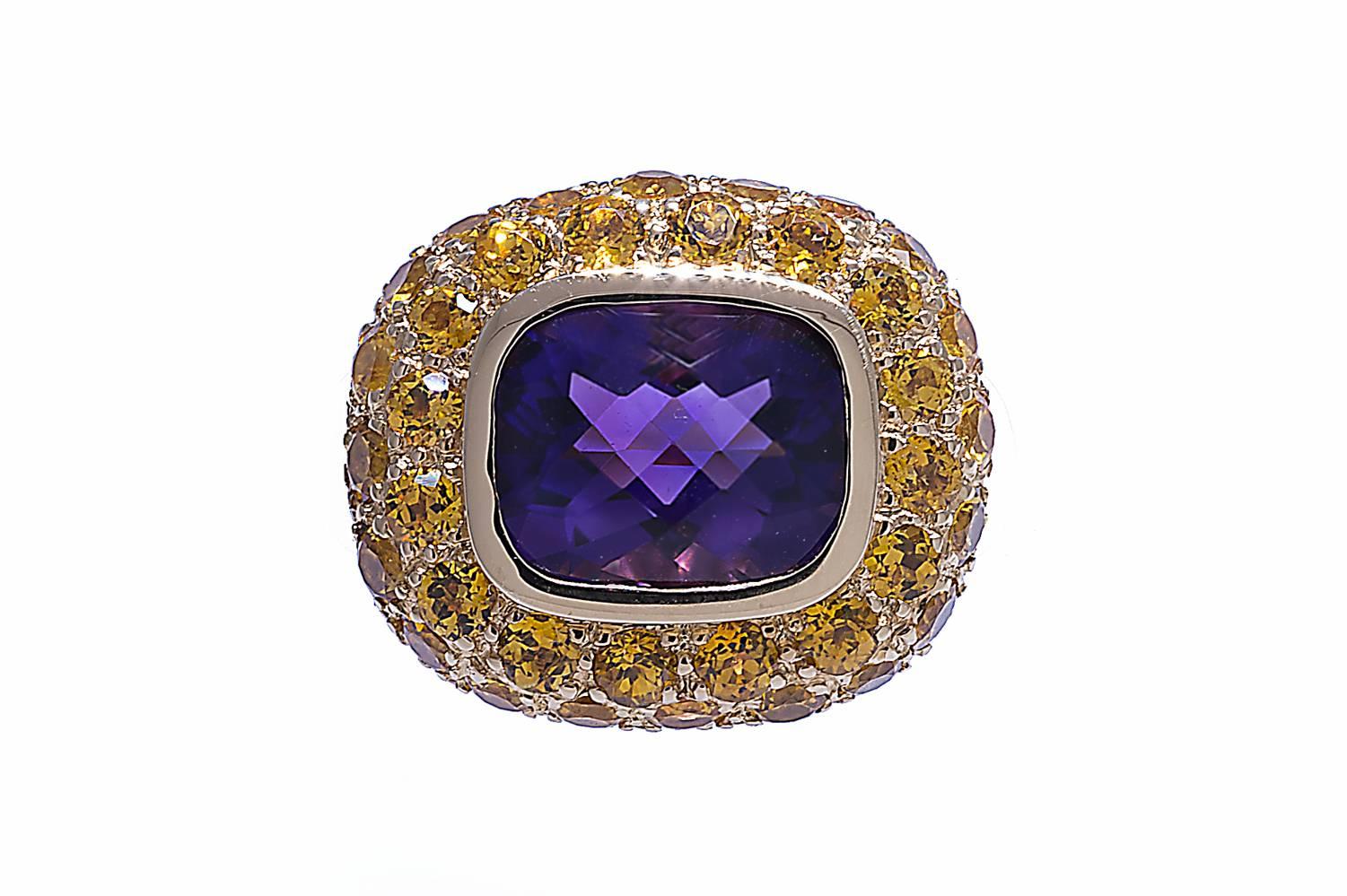 18K yellow gold ring contains a 2.74 carats cushion shape checkerboard cut amethyst. The amethyst is bezel set. The ring also contains 3.85 carats of pave set yellow sapphires. The shank is 6.5mm on top and tapers down to 4mm on bottom. The ring is