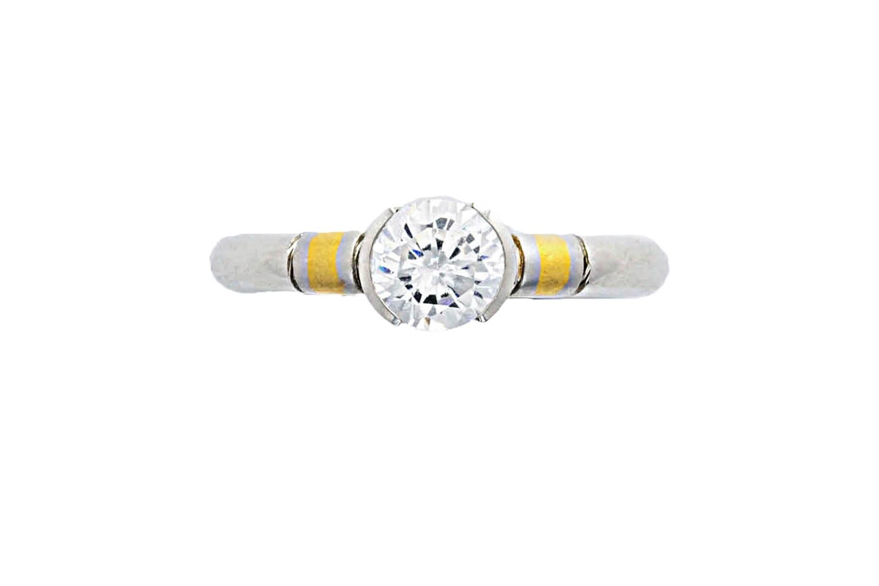 Platinum diamond ring with 18k gold inlay. The round brilliant cut diamond weighs 0.71 carat, H color, SI2 clarity and is set in partial bezel. On each side of the diamond there is a satin finish yellow gold inlay accent.  Simple, unique and